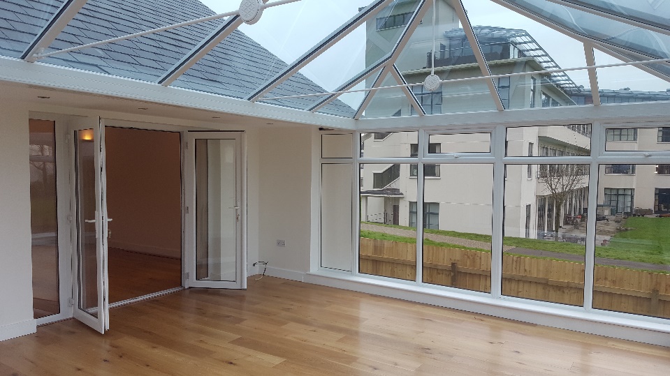 French doors opening to a solarium with light wood vinyl planks.